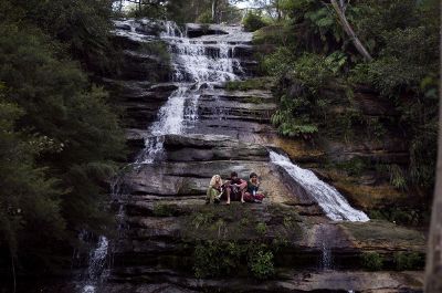 teens sitting by a mountainous waterfall