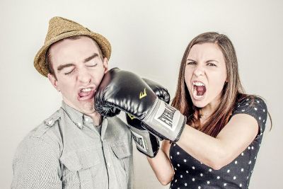 angry woman punching a man in a hat