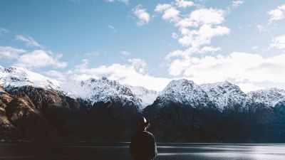 man looking at mountains on lake
