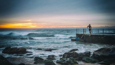 man overlooking water at sunset