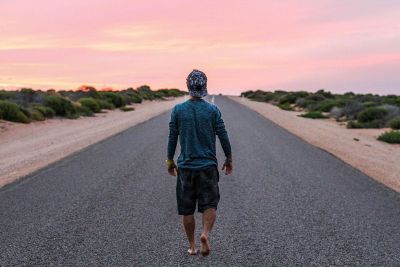 man walking down a road at dusk
