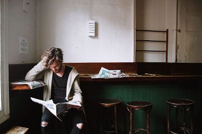 hipster man reading paper at bar