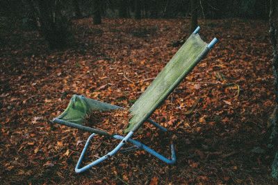 a green lawn chair on top of fall leaves