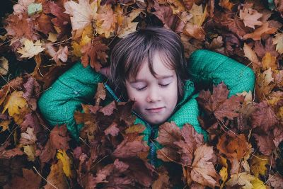 child relaxing in pile of leaves