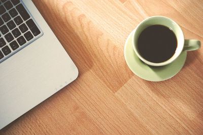 green cup of coffee and macbook on the table