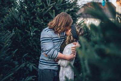 two lovebirds kissing while christmas tree shopping