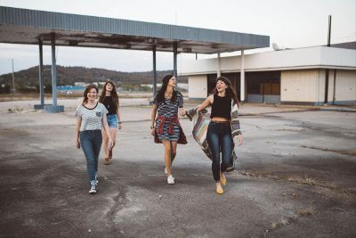 girls walking across closed gas station