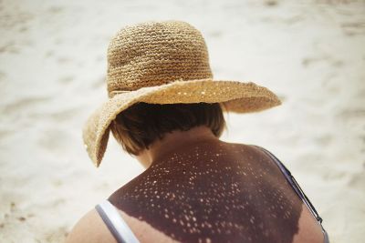 woman with hat sitting in sand