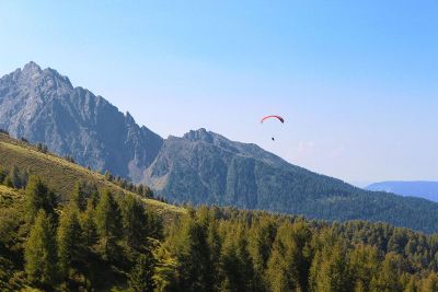 skydiver with parachute over mountains