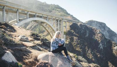 girl sitting on rock under bridge