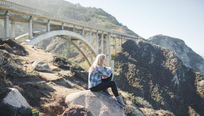 girl sitting on rock under bridge