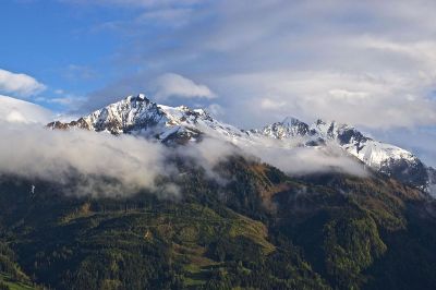 snow peaked mountain scene peering over clouds