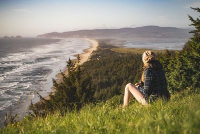 woman viewing chilly shoreline from a verdant cliff