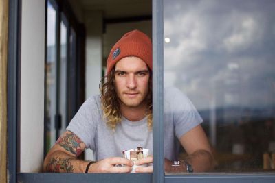 young man with hat and tattoos looking out the window