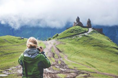 photographing building on lush hill