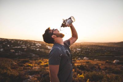 man excitedly drinking from water bottle