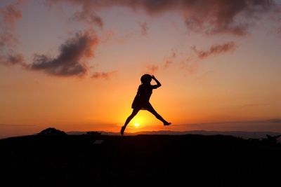 person skipping over sunset
