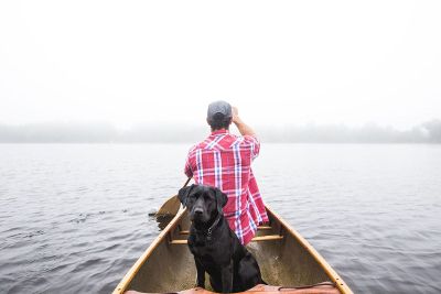 man and dog in boat