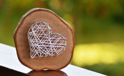 a wood slice with a heart made of nails and string