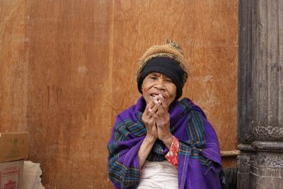 old woman sitting by house