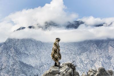 person wrapped in blanket on mountaintop