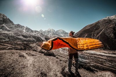 man with sleeping bag in mountains