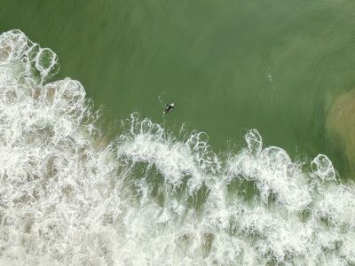 surfer paddles ahead of waves