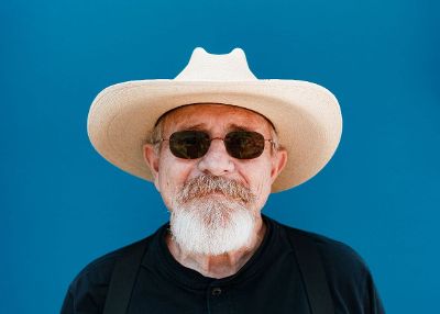 older man with glasses and hat