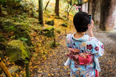 kimonoed woman checks phone in forest