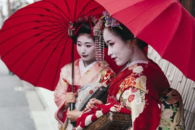 two geisha holding red umbrellas